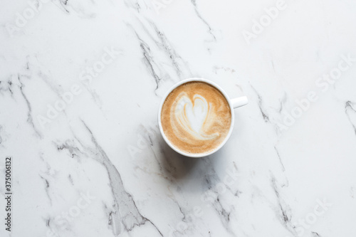 flat white coffee with a loveheart shape, on a marble background photo