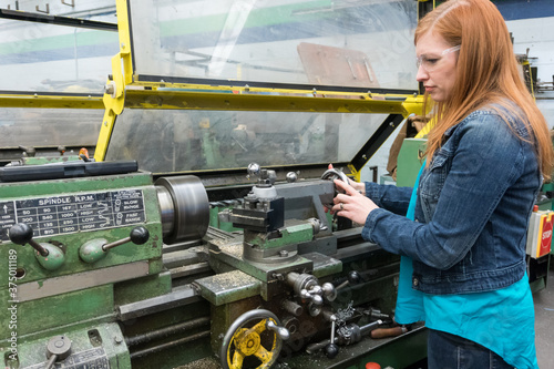 Female company executive hands-on with lathe in machine shop photo