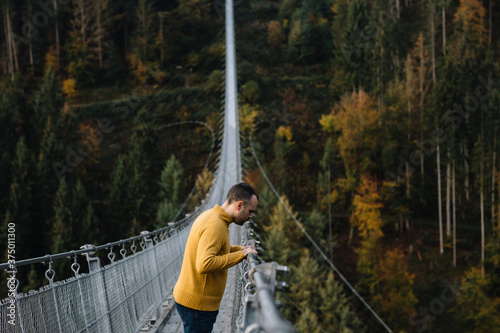 Man standing on a suspension bridge and looking down photo