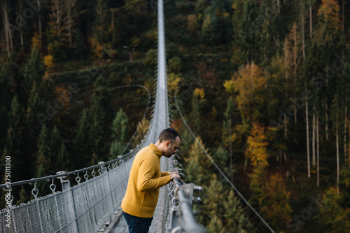 Man standing on a suspension bridge and looking down