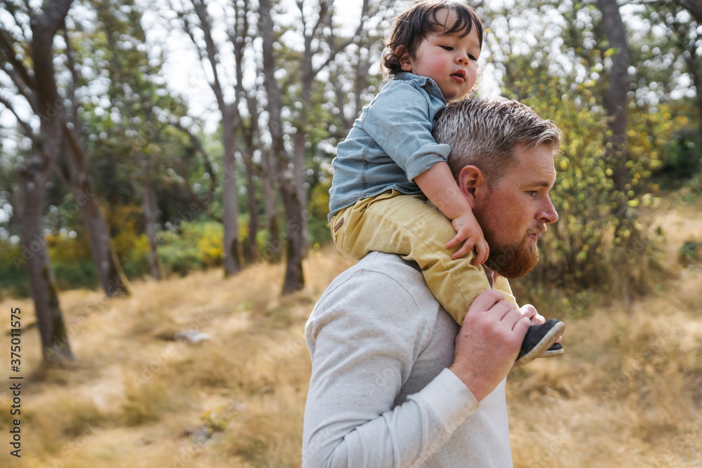 Dad giving shoulder ride to toddler outside
