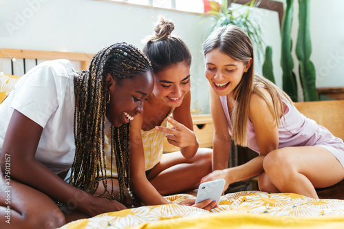 Diverse friends using video chat app on bed