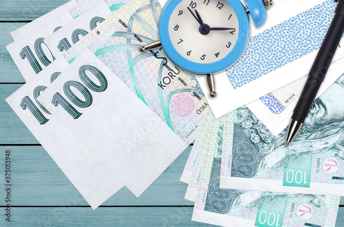 100 Czech korun bills and alarm clock with pen and envelopes. Tax season concept, payment deadline for credit or loan. Financial operations using postal service photo