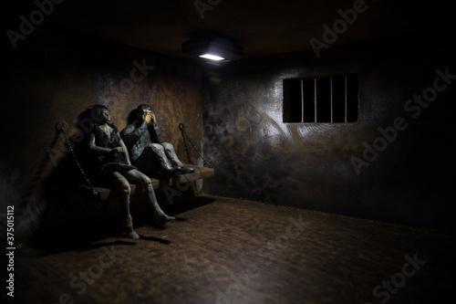 Man in prison man behind bars concept. Old dirty grunge prison miniature. Dark prison interior creative decoration.