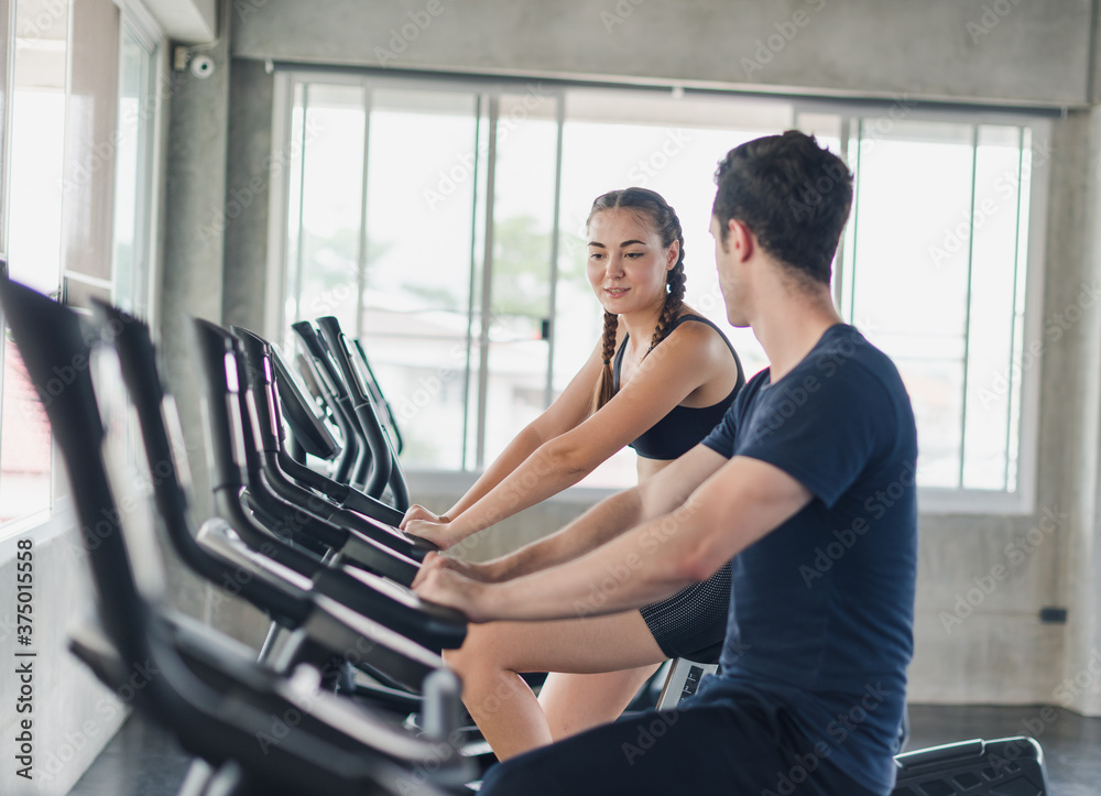 Male and female athletes talk about exercise, cycling in the gym. They wear sportswear to exercise. Male and female athletes talk about exercise, cycling in the gym. They wear sportswear to exercise.