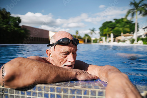 Healthy, retirement-age man breathing hard in the pool. photo