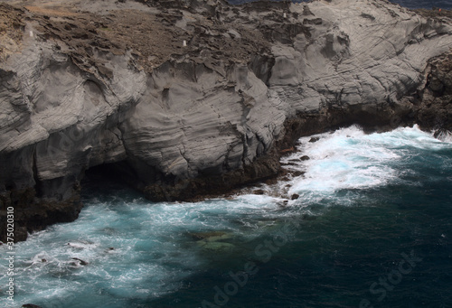North coast of Gran Canaria, Canary Islands, Banaderos area, waves are breaking against elevated rock with salt evaporation ponds Salinas de Bufadero