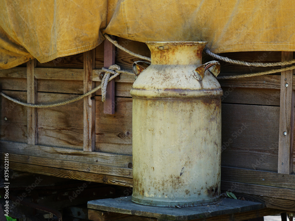Old rusty milk can sitting outside a covered wagon. Old rusty milk can sitting outside a covered wagon.