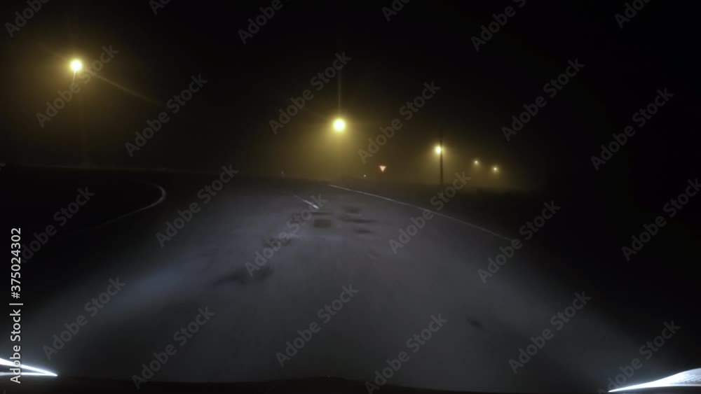 Driving down empty road at night in thick fog