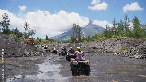 Eye level shot of people riding quad bike atv in Bicol Philippines with Mount Mayon Volcano as background photo