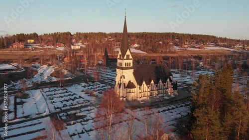 Aerial front view of majestic Scandinavian church/cemetery in Vindeln, Sweden. Shoot on a cold snowy morning. photo