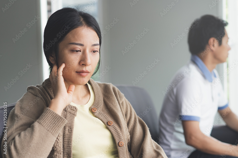 Asian couple having relation problem. Wife sad and sitting separate with her husband at home after quarrel. Asian couple having relation problem. Wife sad and sitting separate with her husband at home after quarrel.