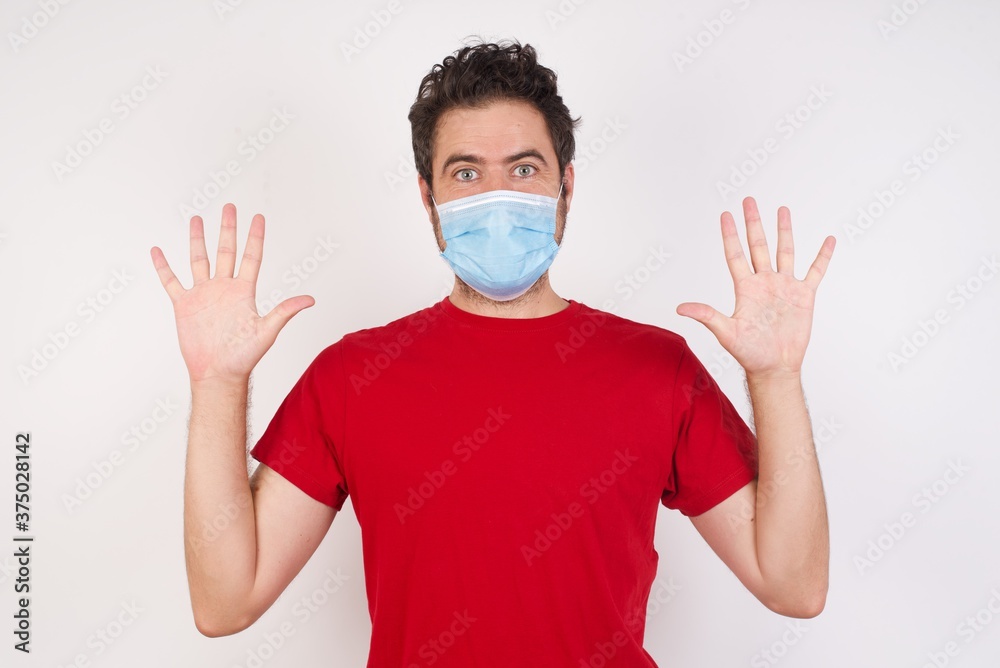Optimistic Young caucasian man with short hair wearing medical mask raises palms from joy, happy to receive awesome present from someone, shouts loudly, Excited caucasian male screaming. Optimistic Young caucasian man with short hair wearing medical mask raises palms from joy, happy to receive awesome present from someone, shouts loudly, Excited caucasian male screaming.