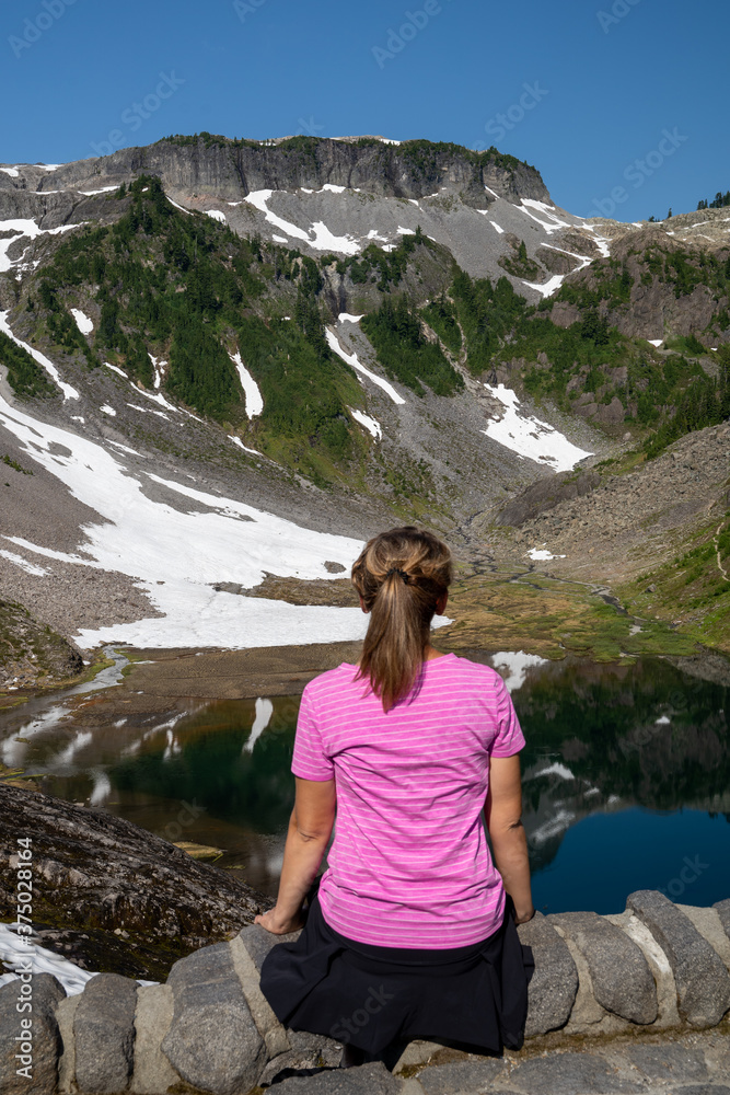 Woman with back facing camera enjoys the view at Heather Meadows in Mt Baker National Recreation Area, Washington State