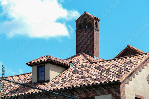 A clay tiled roof with a tower behind