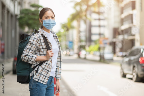 New normal of traveler. Alone young asian beautiful woman travel in holiday with backpack and wearing protection mask virus for safety trip. She walking alone in the city.