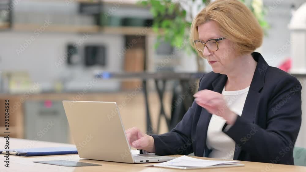 Focused Old Businesswoman working on Laptop and Documents Focused Old Businesswoman working on Laptop and Documents