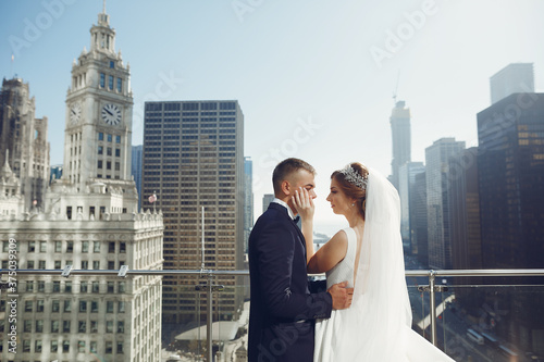 Elegant bride in a white dress and veil. Handsome groom in a blue suit. Couple in a big town