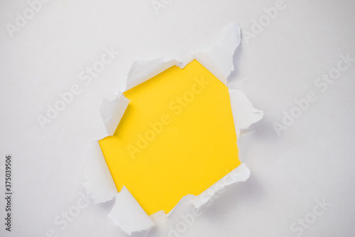 The abstract is full of holes with a white paper on yellow background for concept design with space for your text. A torn piece of paper.