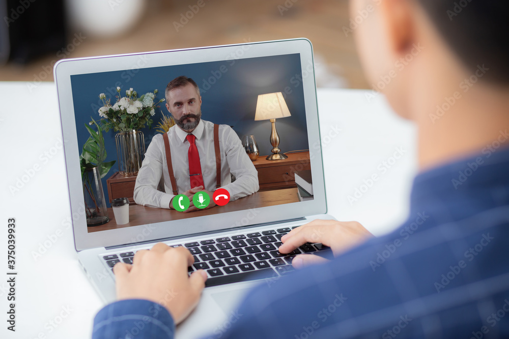 Young asian businessman video conference and discussion with businessman, man work from home with laptop computer with social distancing, meeting online, communication and business concept. Young asian businessman video conference and discussion with businessman, man work from home with laptop computer with social distancing, meeting online, communication and business concept.