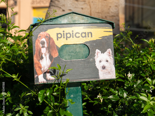 At a shopping center in Spain there is this green box for dog waste on a bush, which looks like a mailbox. Translation of pipican is dog toilet. photo