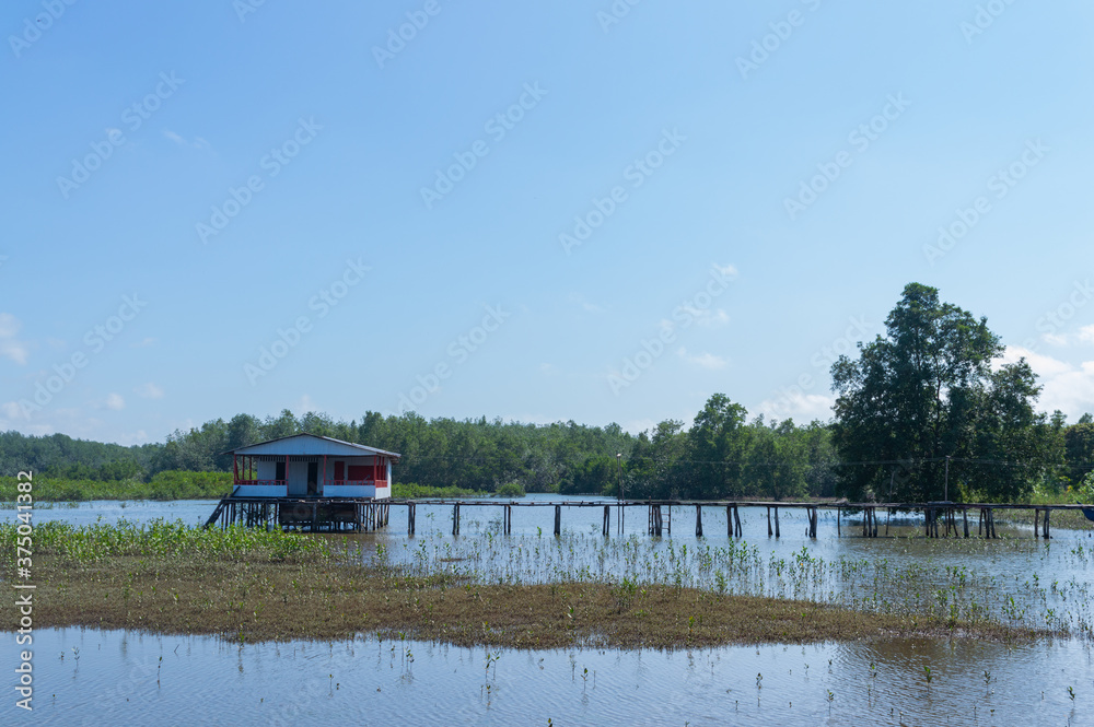 House on a lake with a long bridge and a blue sky