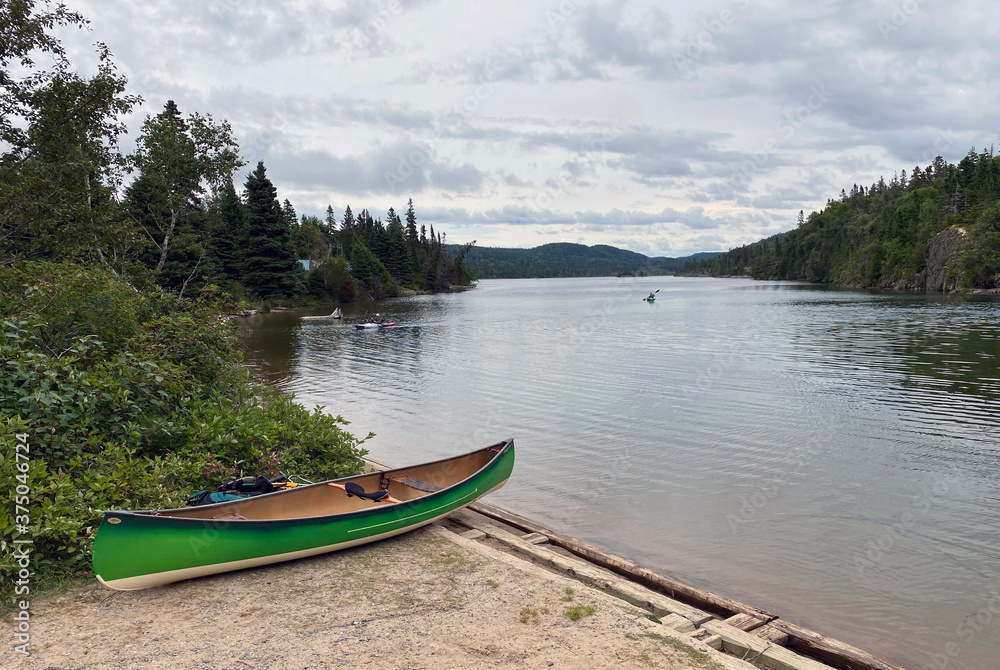 Canoe on shore and kayakers on the water in Pukaskwa National Park in nothern Ontario, Canada