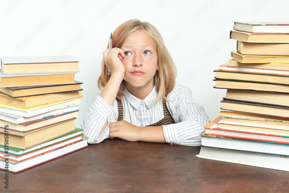 Portrait of a teenage girl, at a table among the books. Looks tiredly away. Portrait of a teenage girl, at a table among the books. Looks tiredly away.