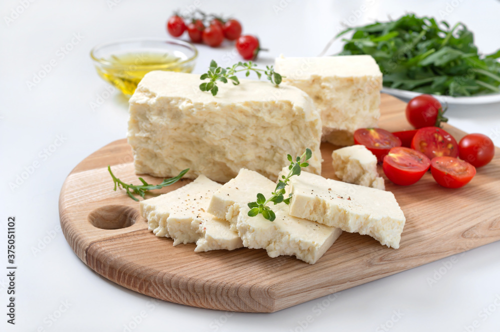 Tasty healthy sheep or goat feta cheese. Chunks of cheese on a wooden board on white background.
