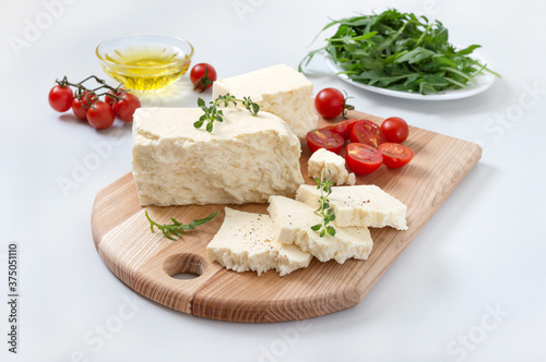 Tasty healthy sheep or goat feta cheese. Chunks of cheese on a wooden board on white background.