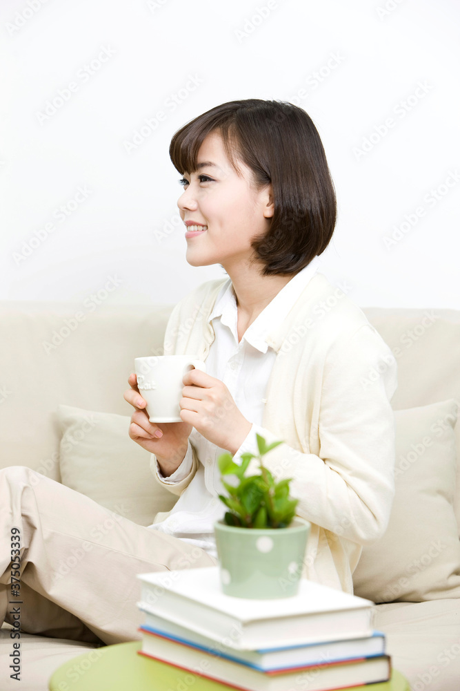 young woman sitting on sofa with teacup young woman sitting on sofa with teacup