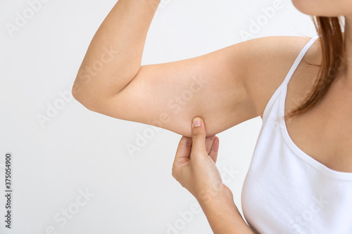 Young Asian woman pinching loose skin or flab on her upper arm Fototapet
