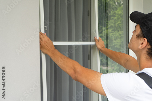A worker Install Mosquito Net on Windows. Protection from flying insects