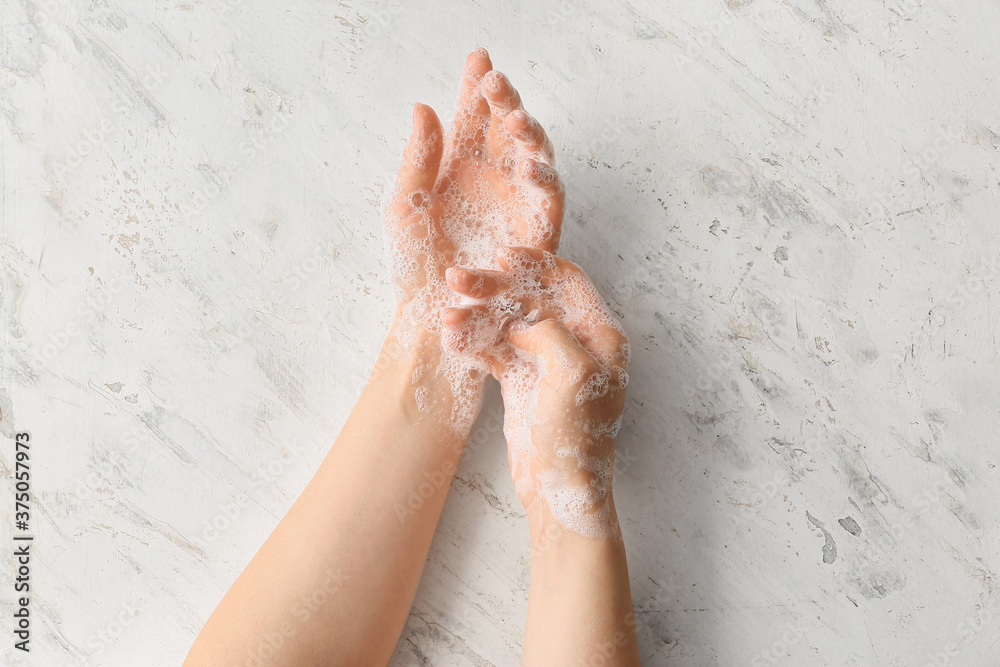 Young woman washing her hands on light background Young woman washing her hands on light background