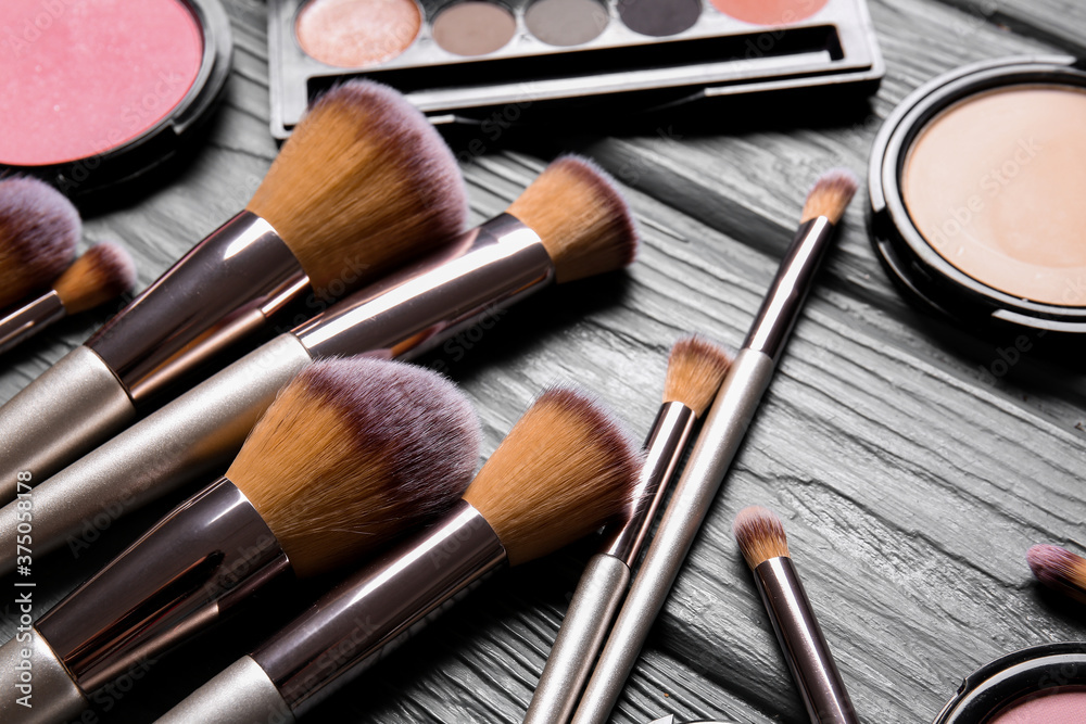 Set of makeup brushes and cosmetics on wooden background, closeup Set of makeup brushes and cosmetics on wooden background, closeup