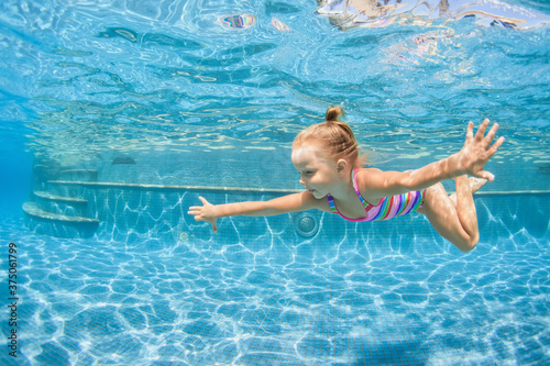 Foto Funny portrait of child learning swimming, dive in blue pool with fun - jumping deep down underwater with splashes