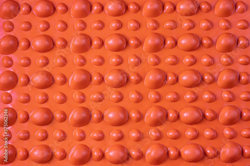 Orange orthopedic mat in the form of small stones on a white background for foot massage. Prevention of children's flat feet