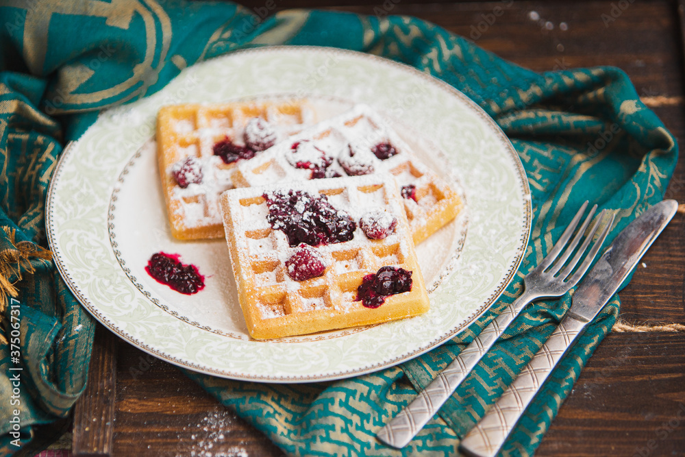 White plate with homemade belgian waffles with Sifting sugar powder over black background. sugar powder over old wooden table. soft focus White plate with homemade belgian waffles with Sifting sugar powder over black background. sugar powder over old wooden table. soft focus