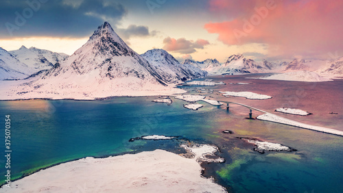 Fabulous winter sunrise on Norway, Europe. View from flying drone of Lofoten Islands archipelago. Colorful morning view of Fredvang bridge with Volandstind peak on background. Life over polar circle.