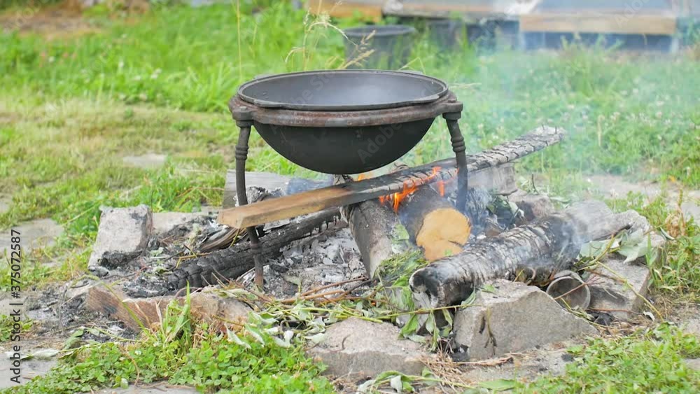 Frying the beef in a cauldron over an open wood fire to prepare pilaf Frying the beef in a cauldron over an open wood fire to prepare pilaf