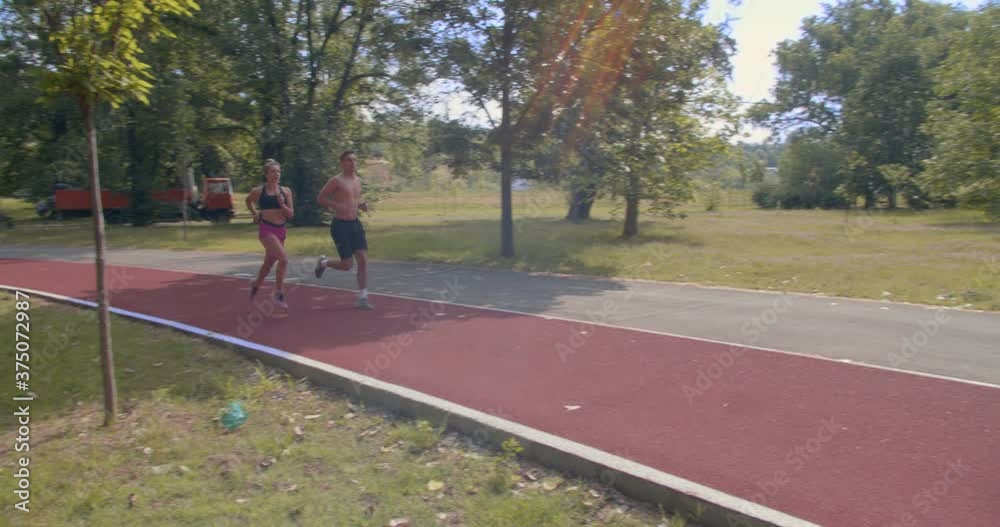 Couple in the park running in a red running path Couple in the park running in a red running path