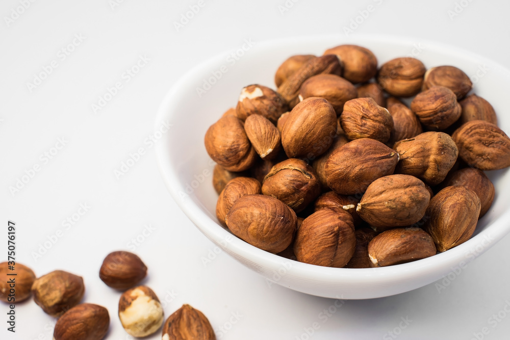 on a light background on the right is a white plate containing yellow nuts on a light background on the right is a white plate containing yellow nuts