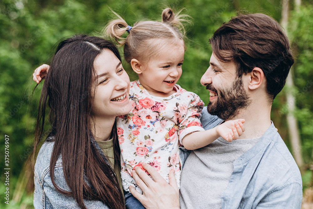 Fototapeta premium Happy stylish family: Photo of a young family enjoying a vacation in a park in a spring countryside
