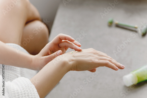 Close up of woman applying cream on her hand.