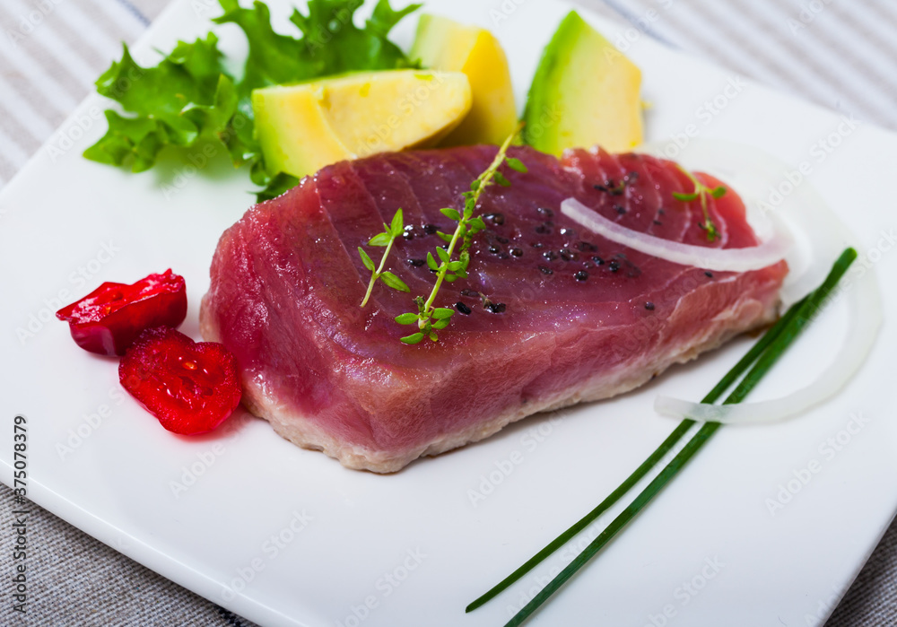 Delicious raw tuna fish served with fresh avocado and greens at plate