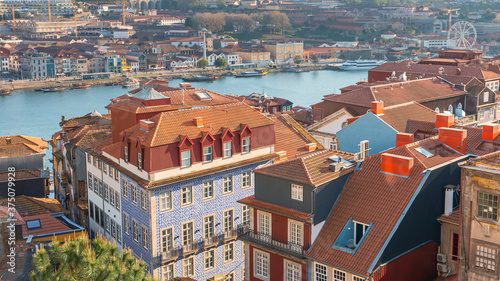 top view of the red tiled roofs of the Portuguese city of Porto in the background of the river with vintage boats