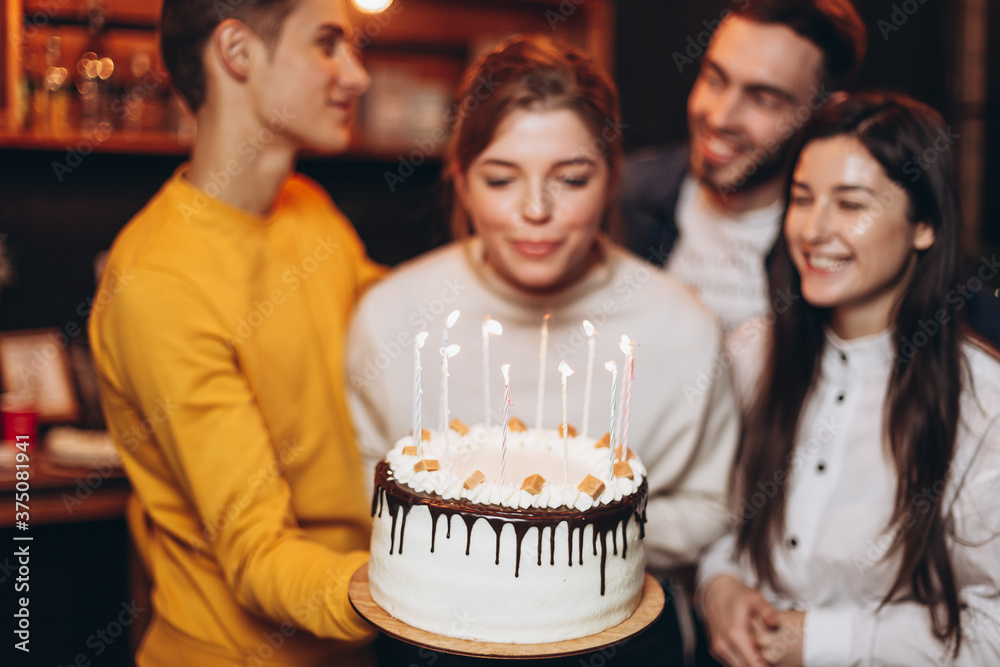 Surprise for her. Group of happy people celebrating birthday party with friends and smiling during party. Smiling attractive girl holding a cake in her hands Surprise for her. Group of happy people celebrating birthday party with friends and smiling during party. Smiling attractive girl holding a cake in her hands