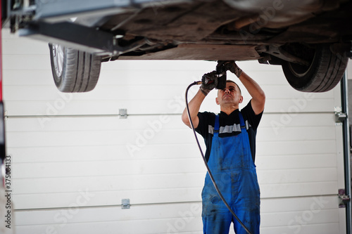 Car repair and maintenance theme. Mechanic in uniform working in auto service.