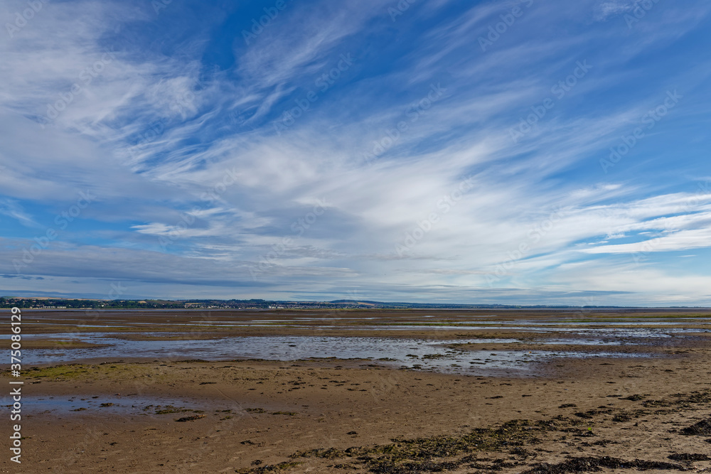 The large flat sandy beach at the Tay estuary near to Tentsmuir Nature Reserve at Low tide, with Barry Buddon in the distance.