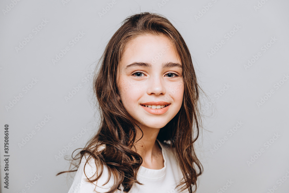 little pretty girl with expressive facial features posing for a photo on a gray background little pretty girl with expressive facial features posing for a photo on a gray background